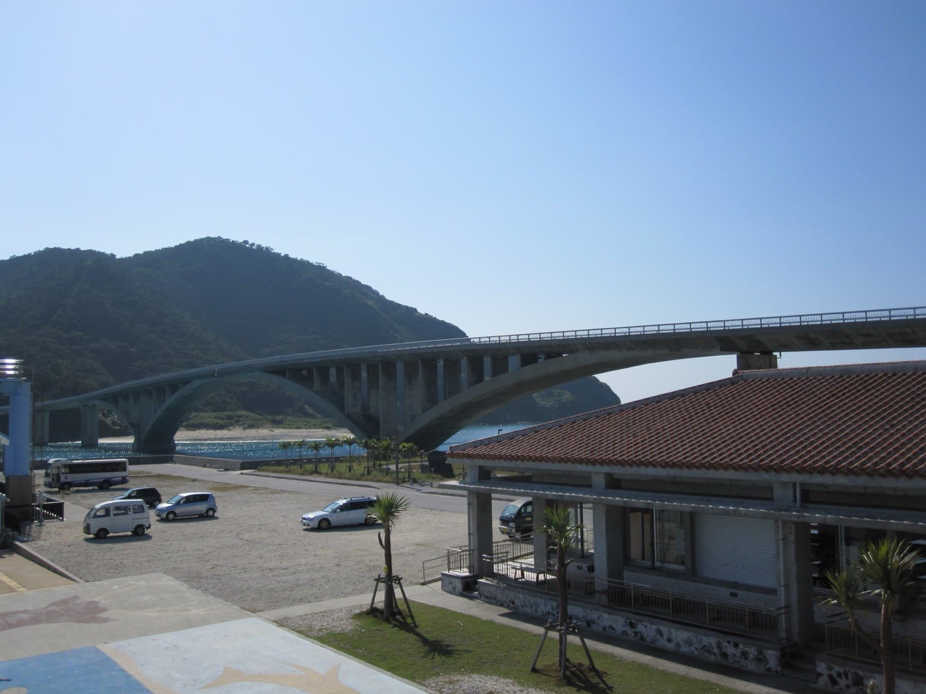 The concrete arches of the Aka Ohashi carry the road from Aka Port across to the green hills of Geruma under a cloudless sky