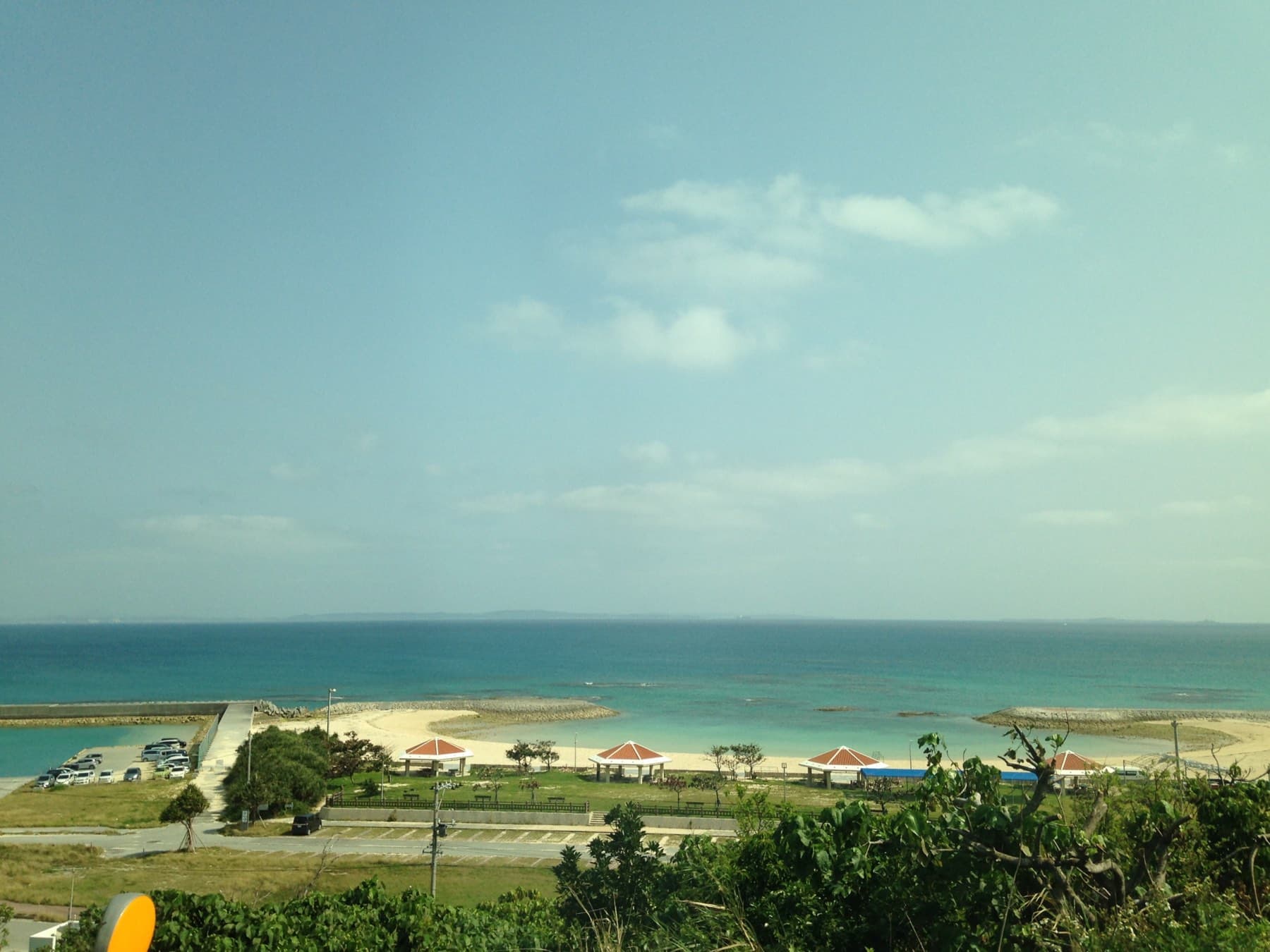 Azama Sun Sun Beach and its red-roofed shelters line the shore below National Route 331 in Chinen, with the reef-edged sea beyond.