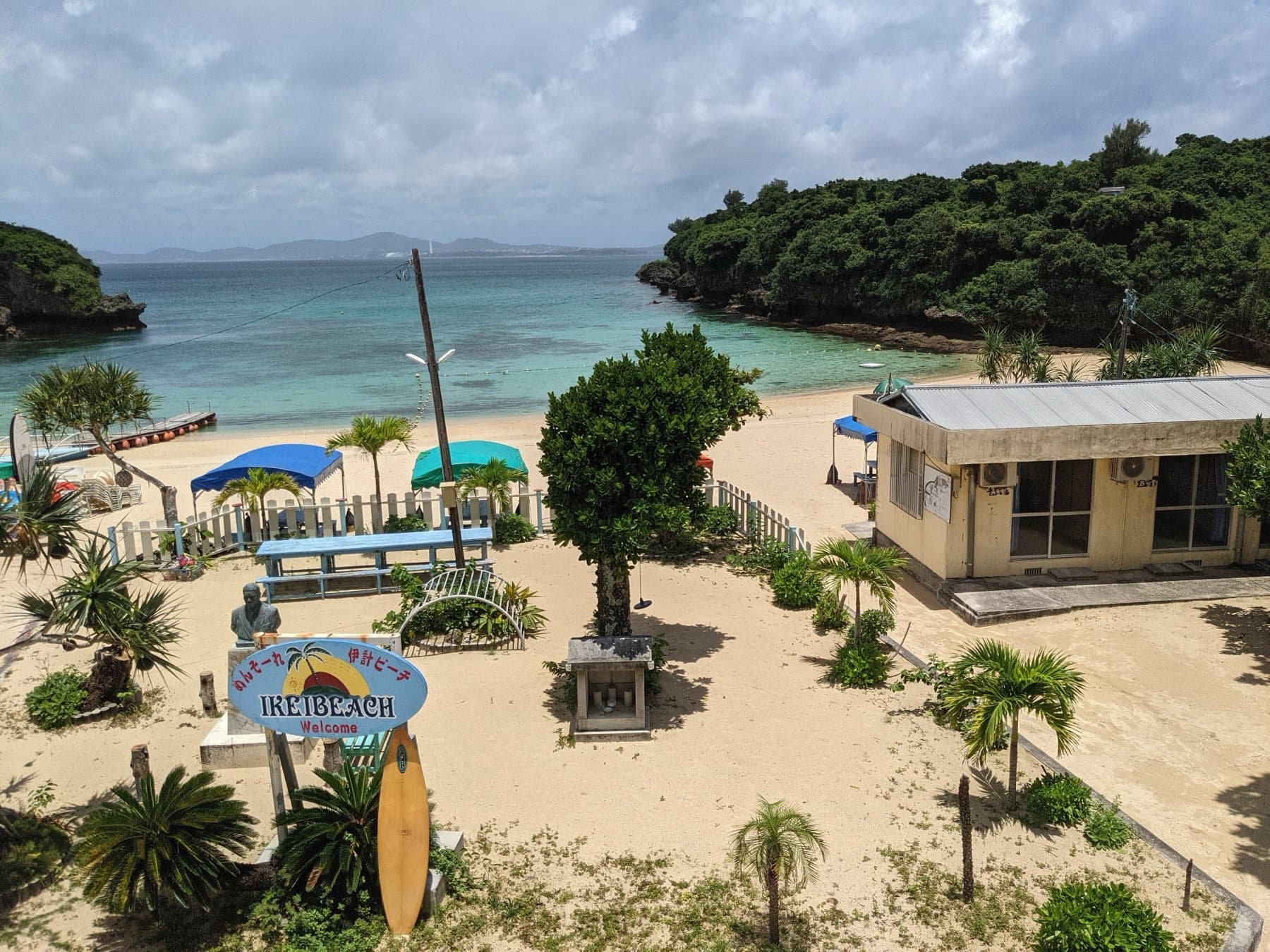 Palms and picnic shelters dot the sand of Ikei Beach in a sheltered cove, and green wooded headlands close the bay on both sides