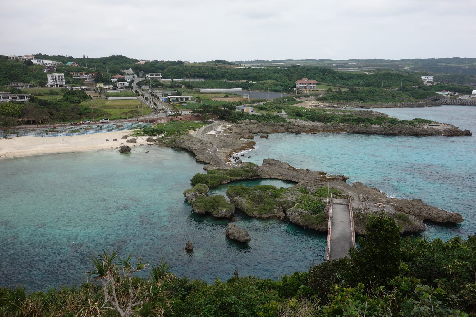 A footbridge crosses the calm lagoon of Imgya Marine Garden, where rocky islets shelter the water from the open sea.