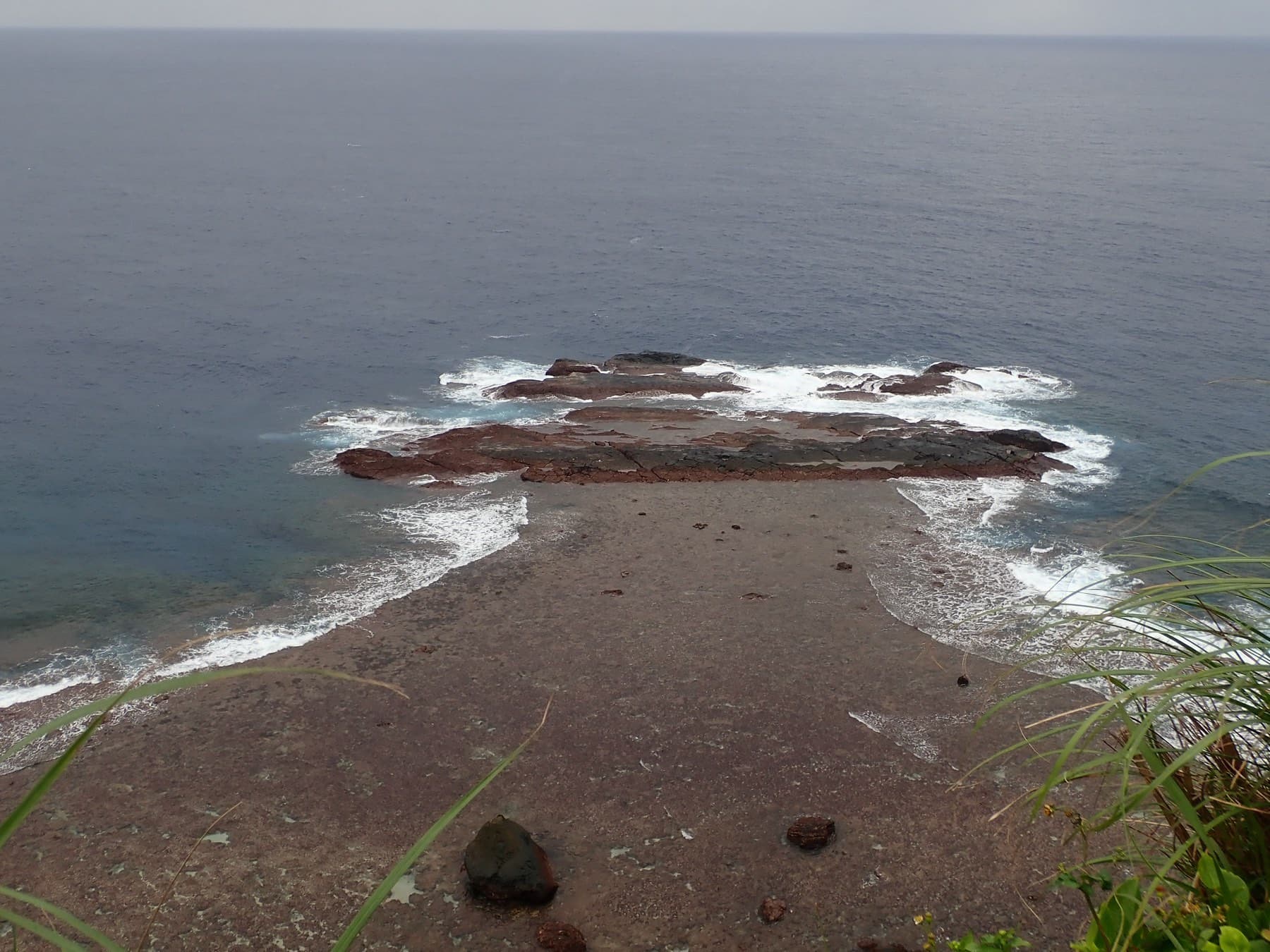 Low tide bares the reef of Tuishi, which runs out from below Irizaki into the grey East China Sea as waves wrap around its tip.