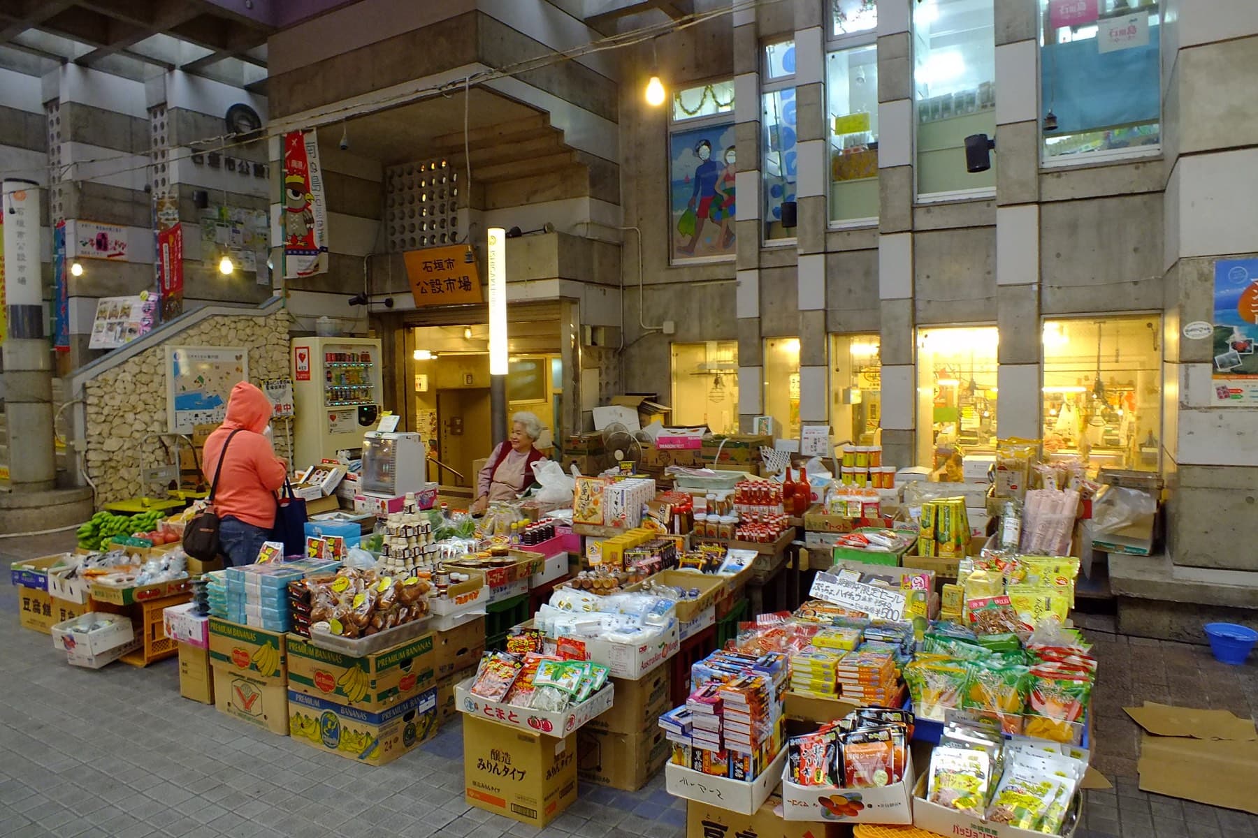 Crates of local produce and packaged snacks spill across the ground floor of the Ishigaki Public Market off the Euglena Mall arcade.