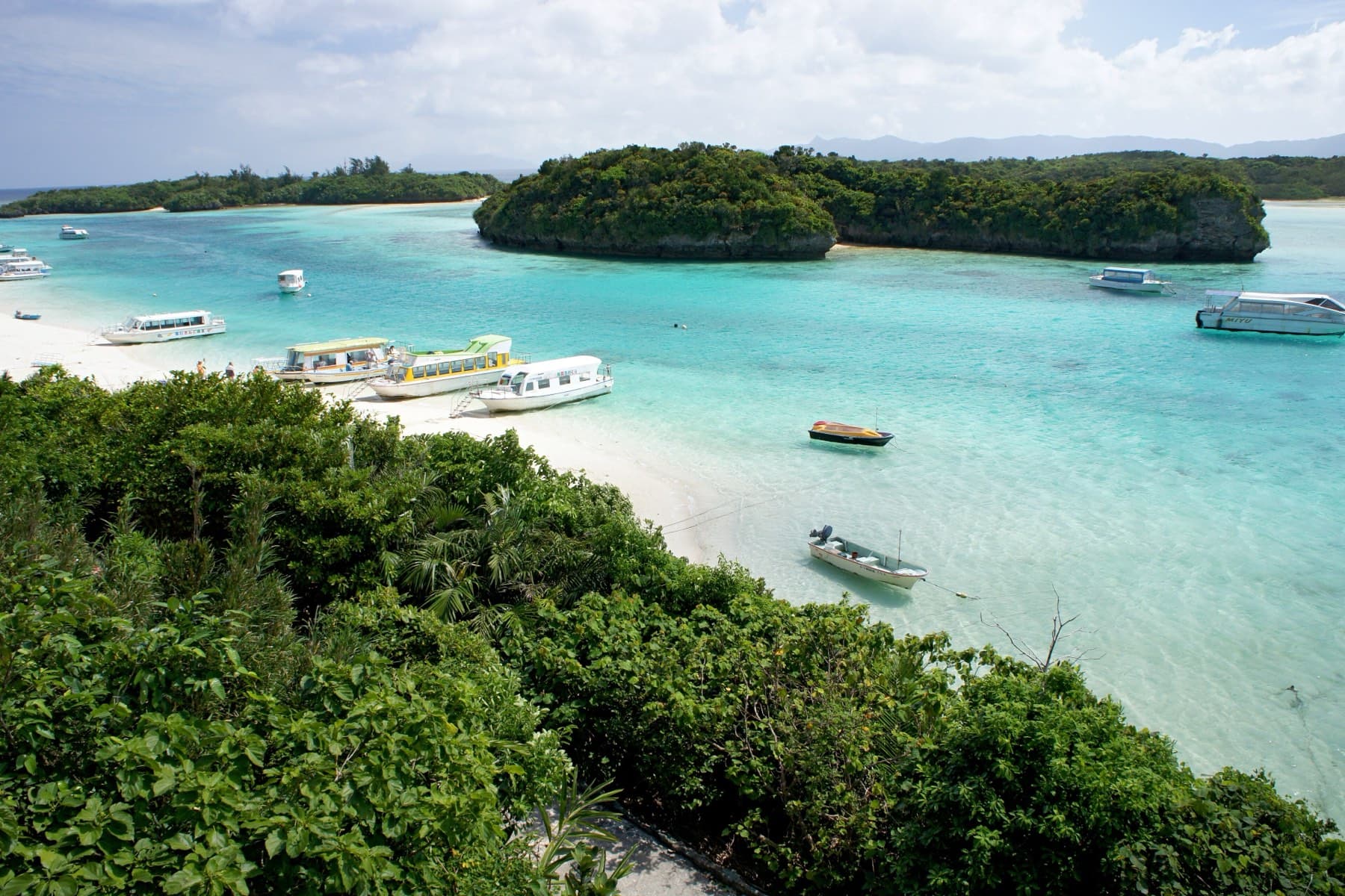 From the slope of Kabira Park the view drops to glass-bottom boats resting on the sand and in the bright shallows below a rounded wooded islet.