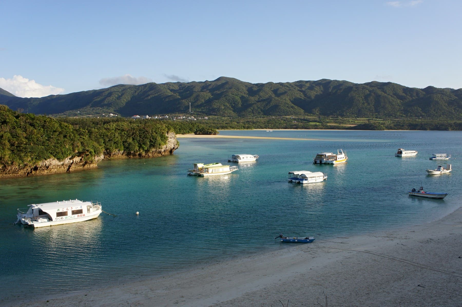 Late afternoon sun lights the boats moored in Kabira Bay and the green ridge of hills that closes the view across the water on Ishigaki.