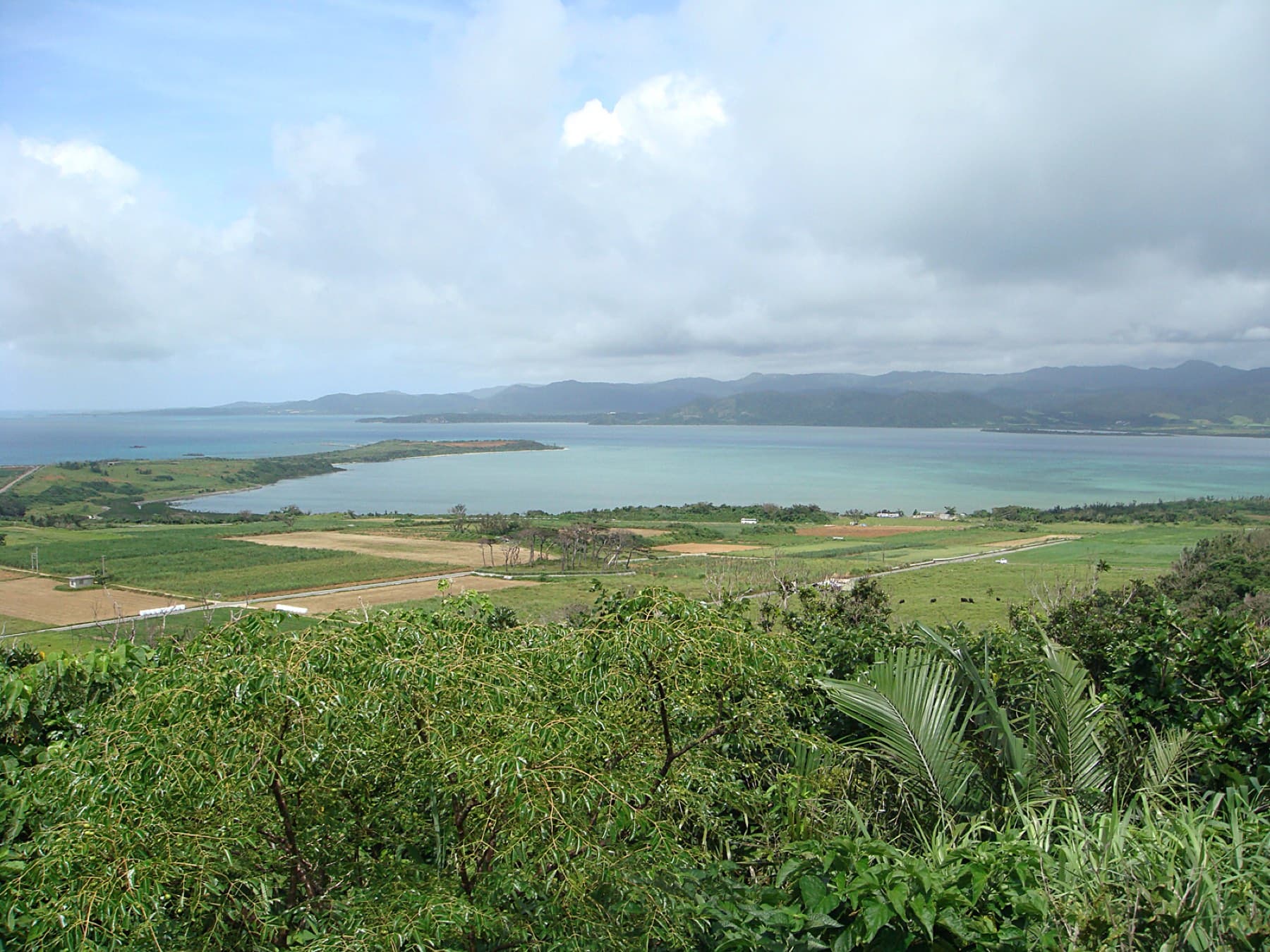 From high ground on Kohama the view runs over fields to the long sand spit of Kubazaki and the pale water of the Yonara Channel.