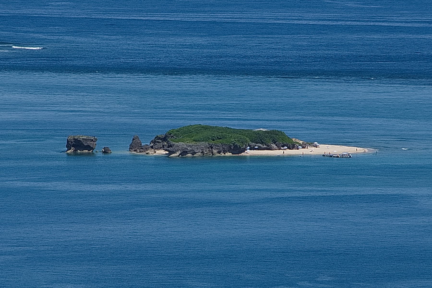The tiny islet of Komaka lies in deep blue water off Chinen, a low hump of green scrub with a strip of white sand at its tip