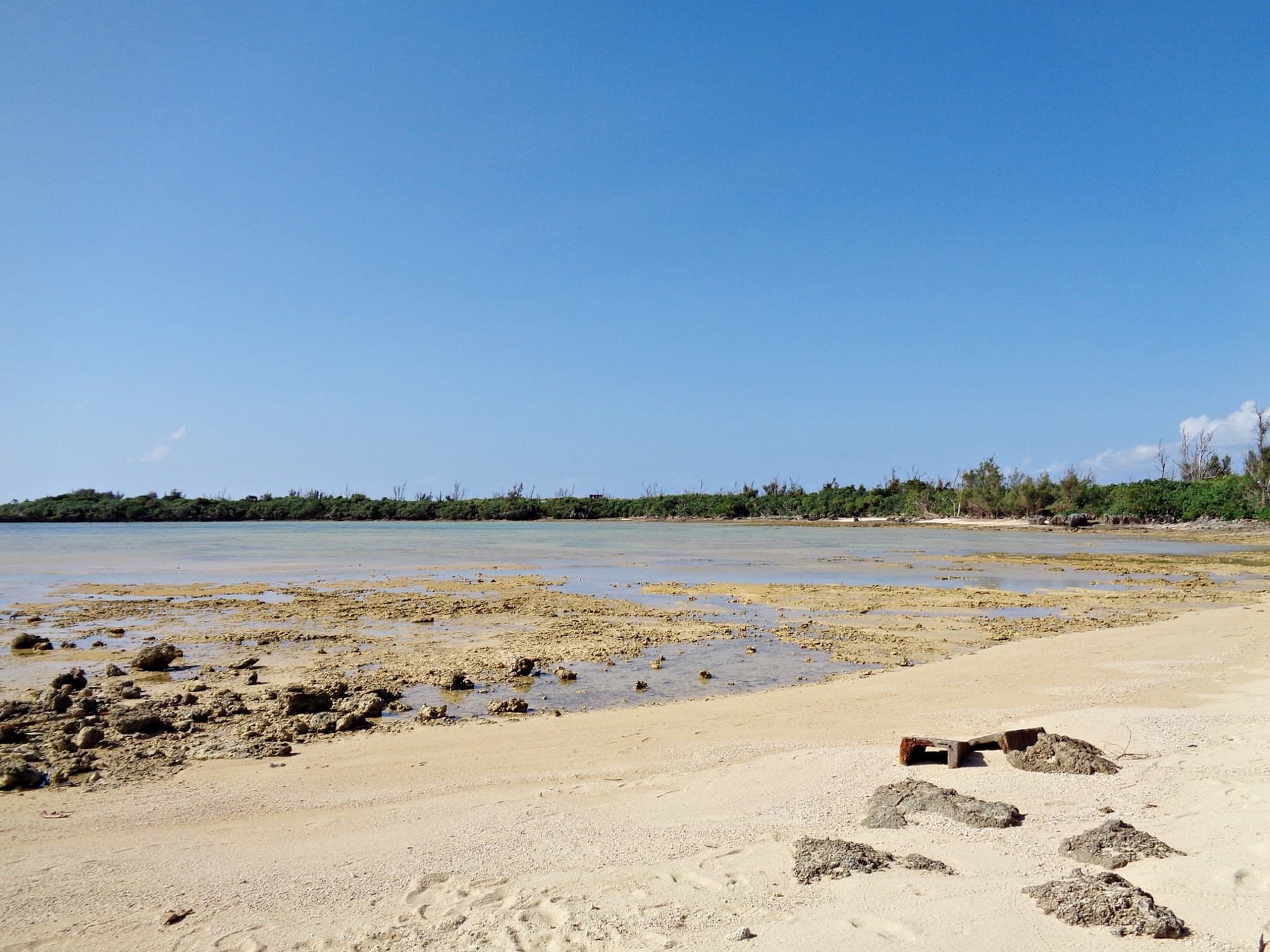 Ripples of clear water run over white sand on Minna's south shore, and the shallows turn pale blue out toward a stone breakwater