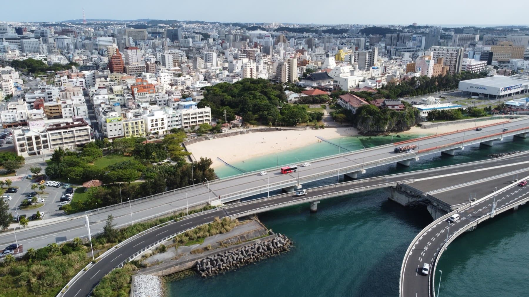 From the air the coastal highway curves past the small pale sand of Naminoue Beach, and the dense white city of Naha stretches inland to the hills