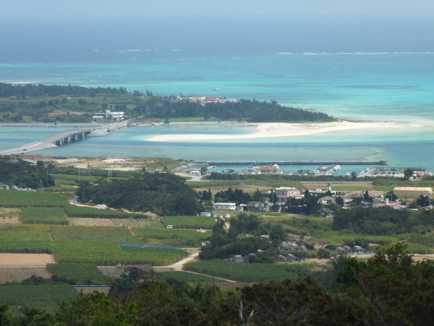 The bridge to Ou-jima crosses a pale turquoise lagoon off Kume's east coast, where a long white sand spit curves past the island's wooded shore