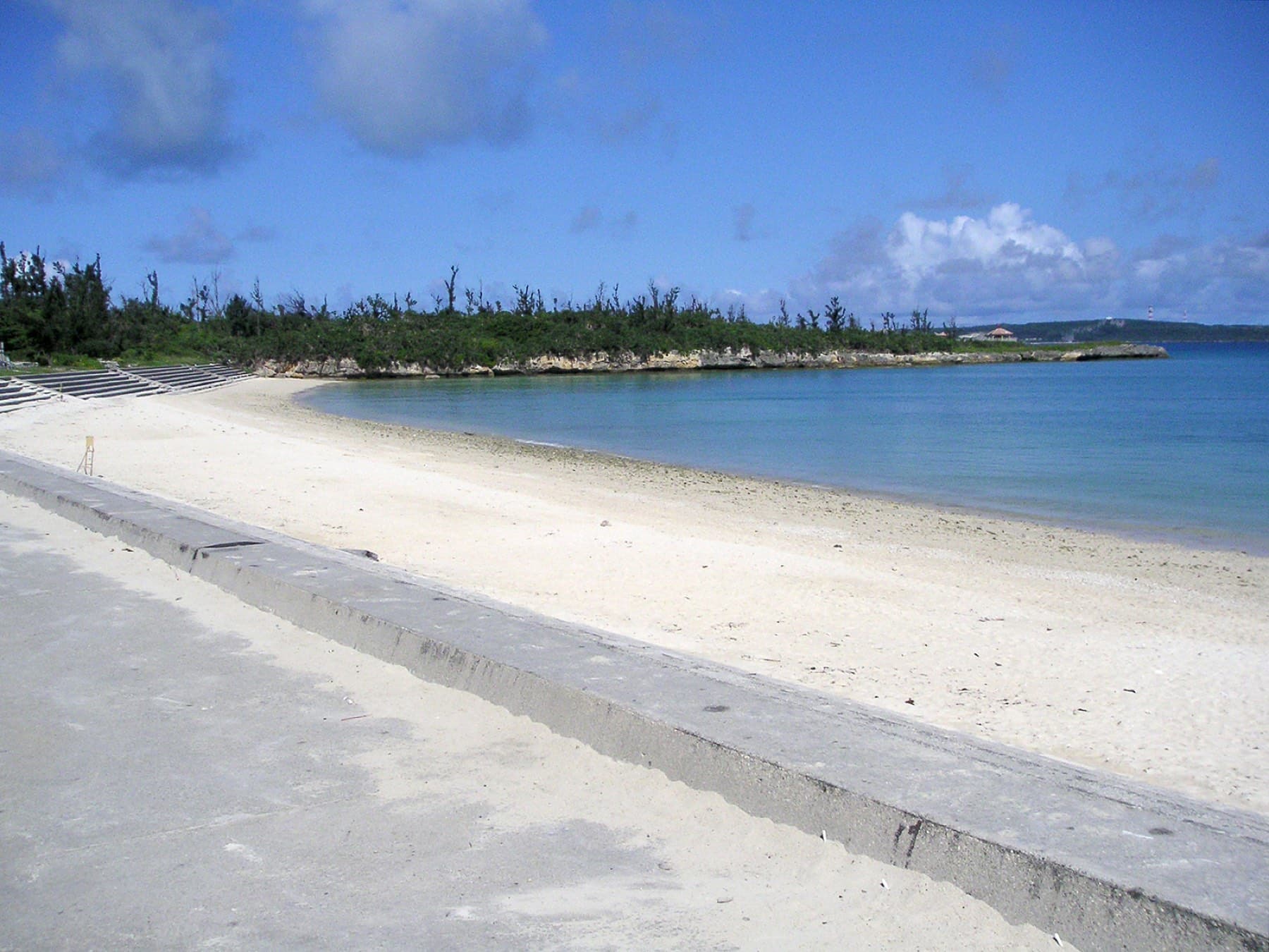 A curve of white sand runs below a low seawall at Painagama Beach, which sits a short walk from the centre of Hirara.