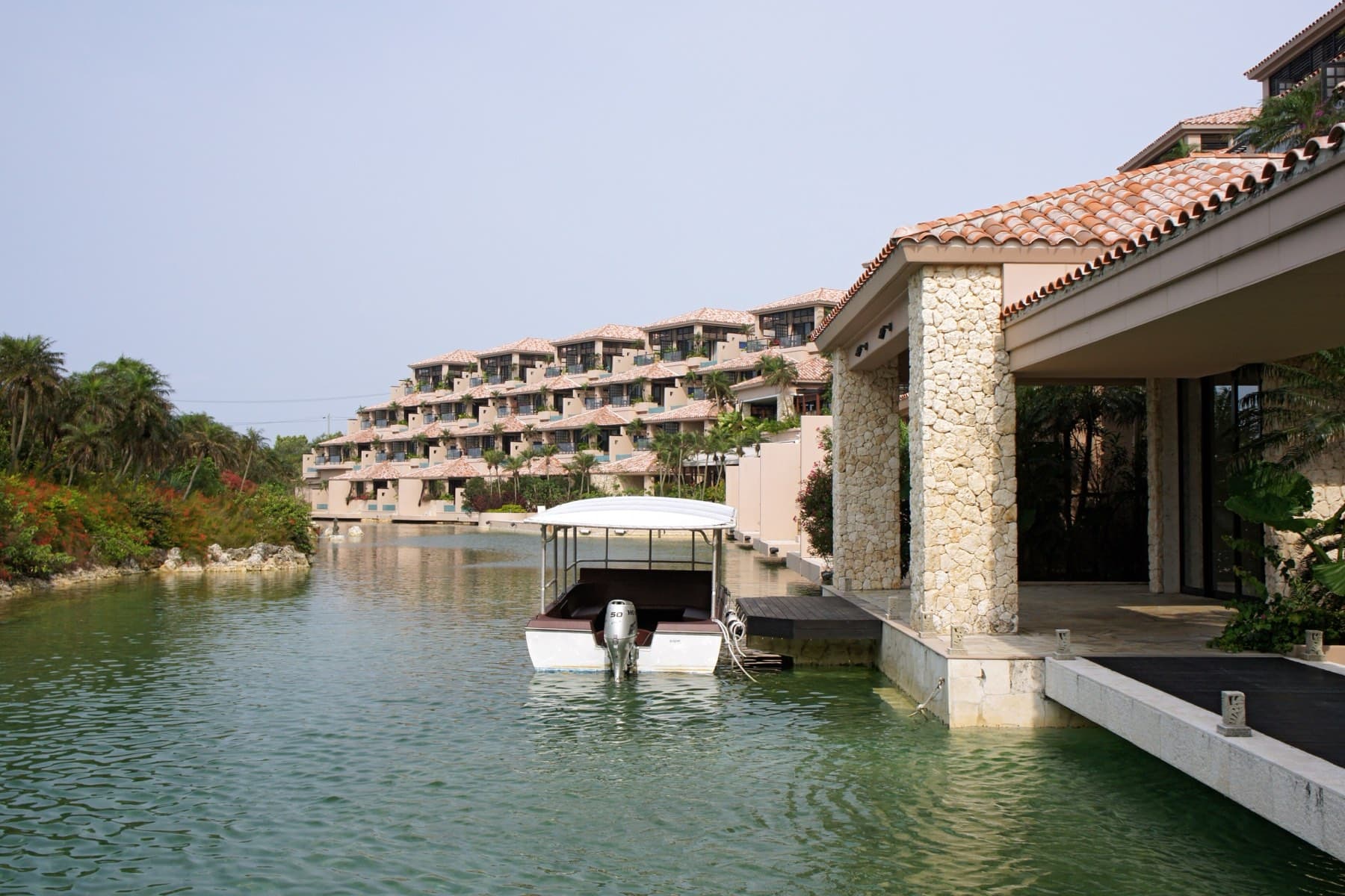 Terraced suites with red-tiled roofs step down to a calm canal of sea water at Shigira Bayside Suite Allamanda on Miyako's south coast.