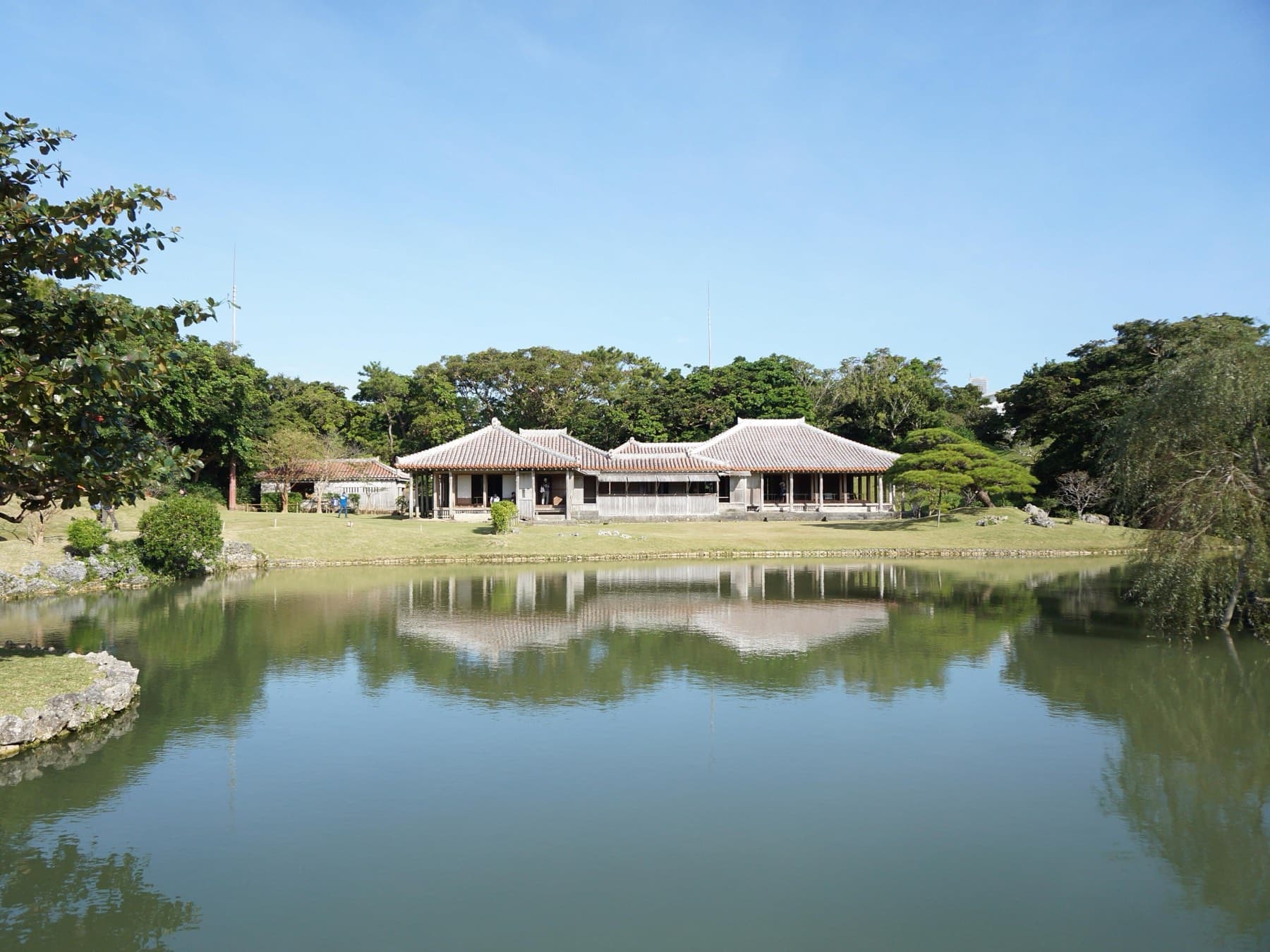 The low red-roofed villa of Shikinaen lies mirrored in the still garden pond under a clear blue November sky