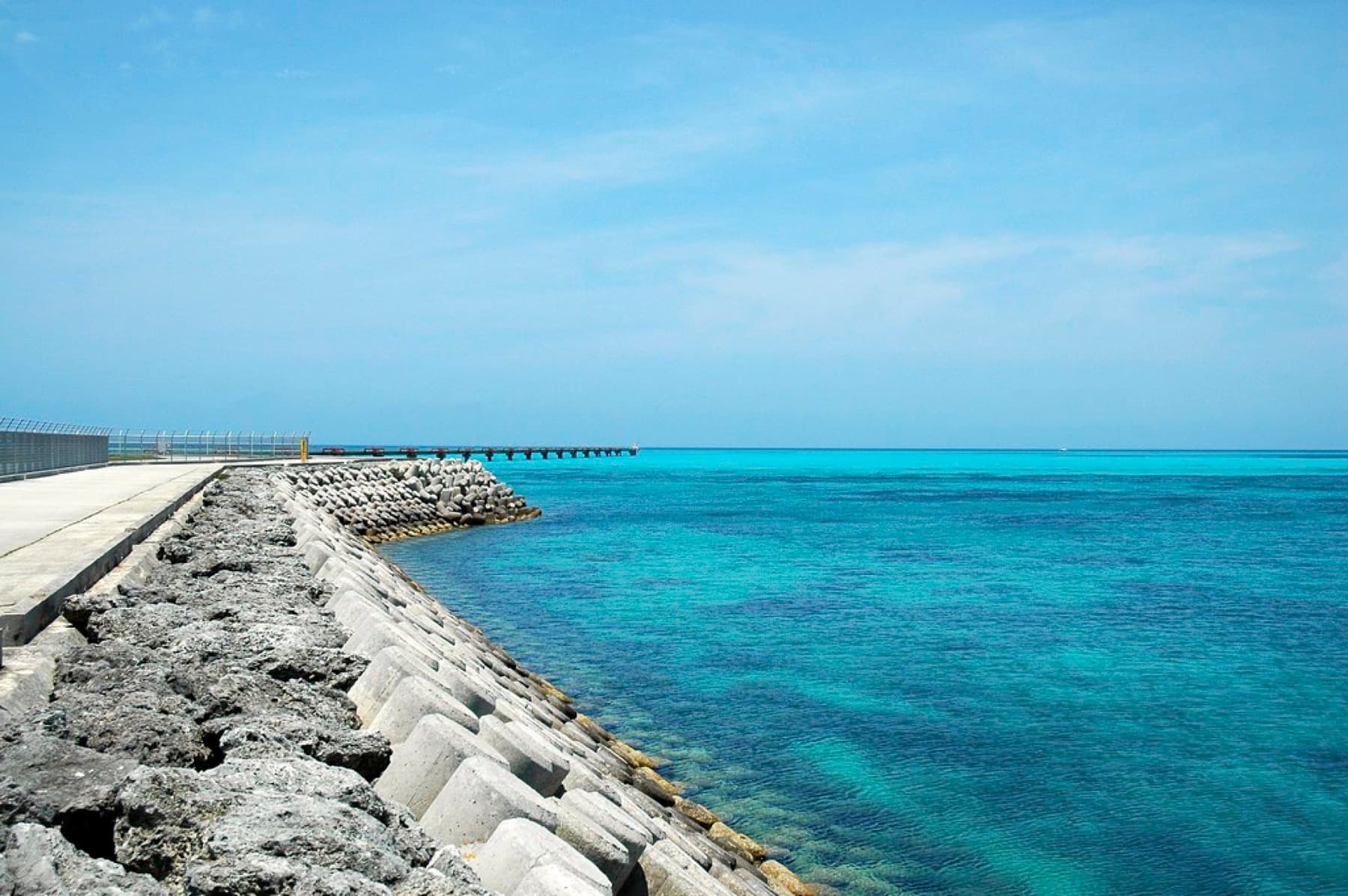 Concrete blocks line the seawall beside the Shimojishima runway as the water off its end shades from turquoise to deep blue.