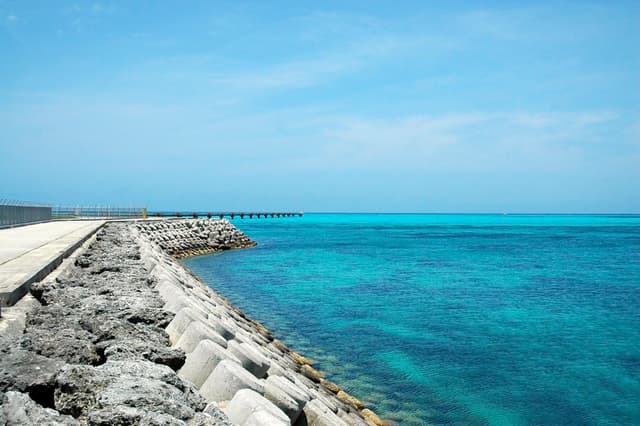Concrete blocks line the seawall beside the Shimojishima runway as the water off its end shades from turquoise to deep blue.