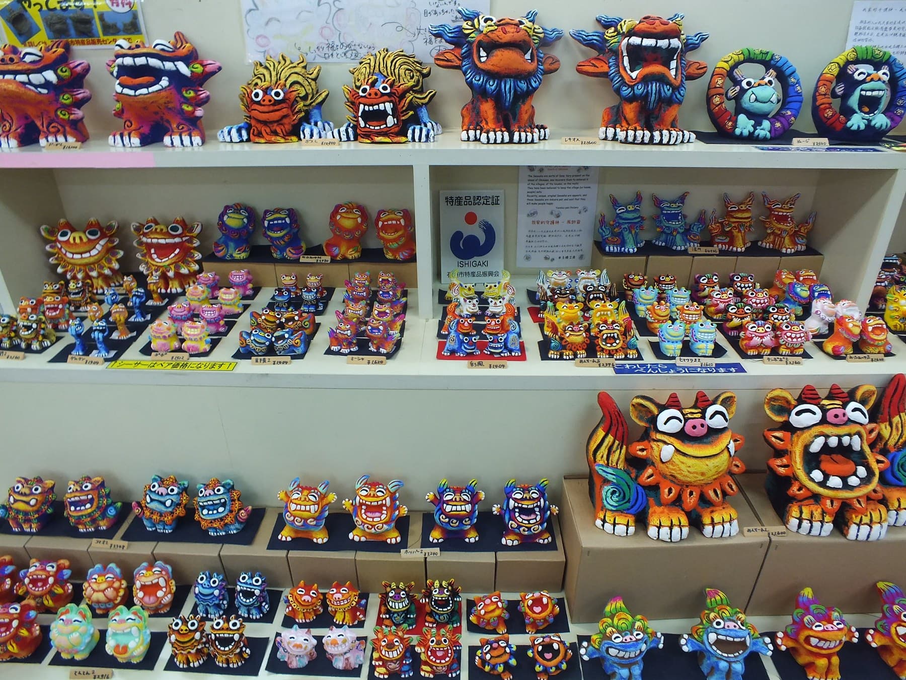 Shelves of brightly painted Yoneko-yaki shisa lions grin from a stall at the Ishigaki Public Market.