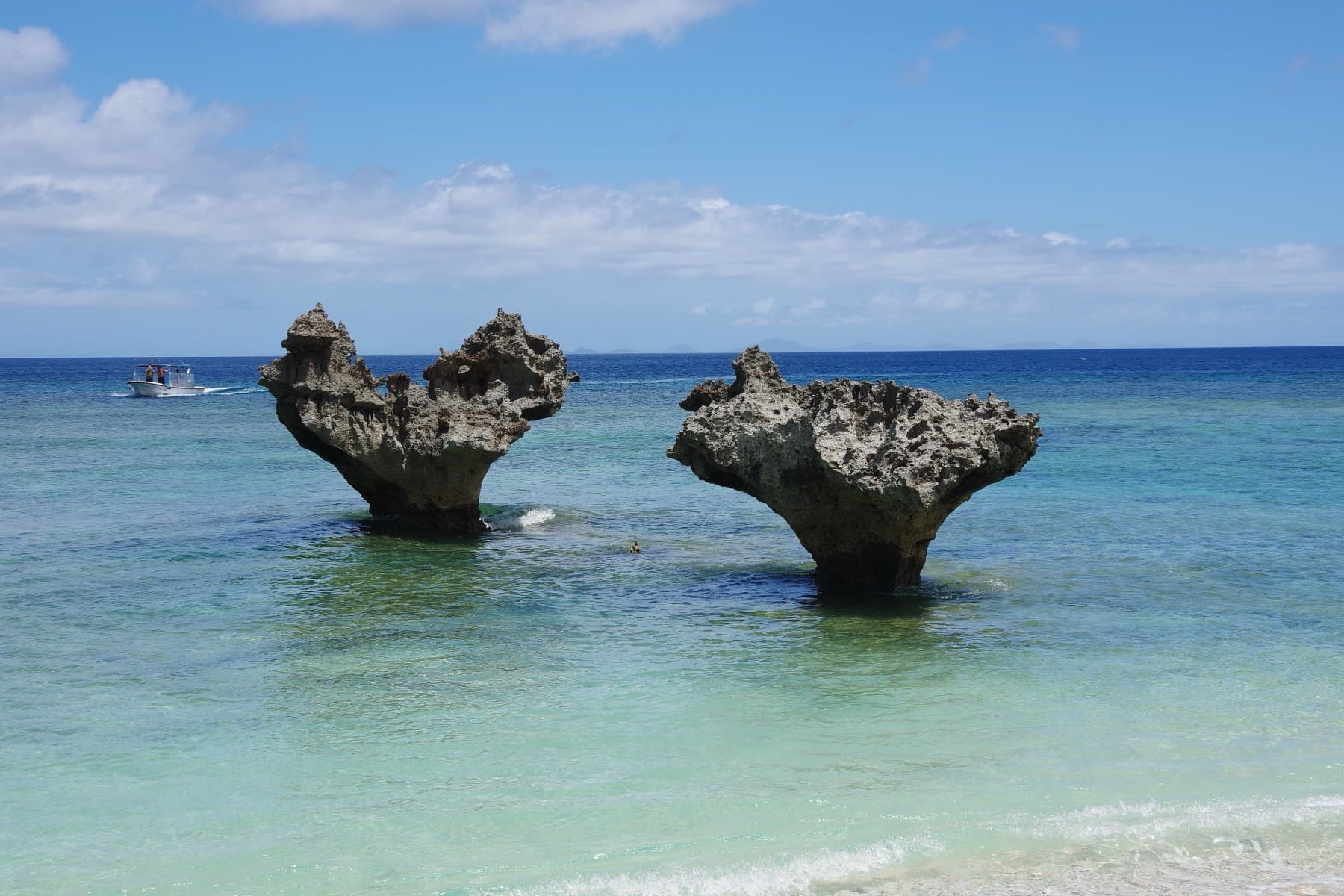 Two wave-cut rocks rise from clear shallow water at Tinu Beach on Kouri's north shore, and their tops line up into the outline of a heart