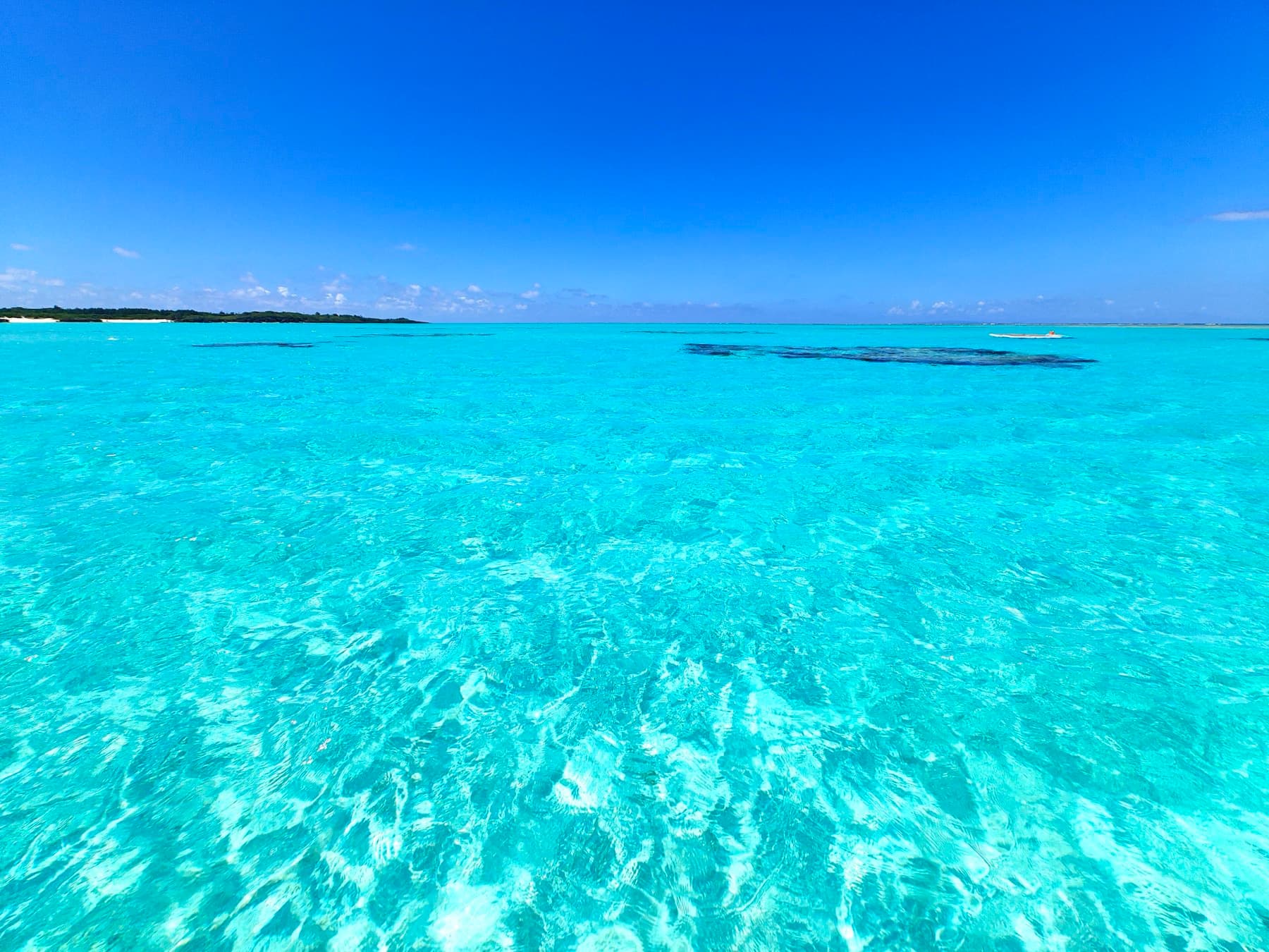 Bright turquoise water over white sand fills the lagoon off Yoron's east coast under a deep blue sky.